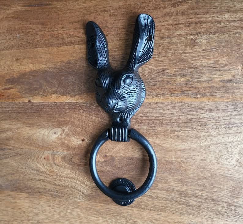 Black rabbit brass door knocker on wood background. Home decor.