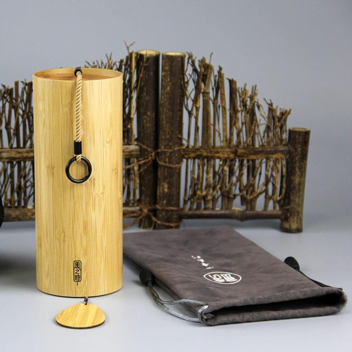 Natural bamboo wind chime with 4 melodies, shown with a decorative bamboo fence and pouch.
