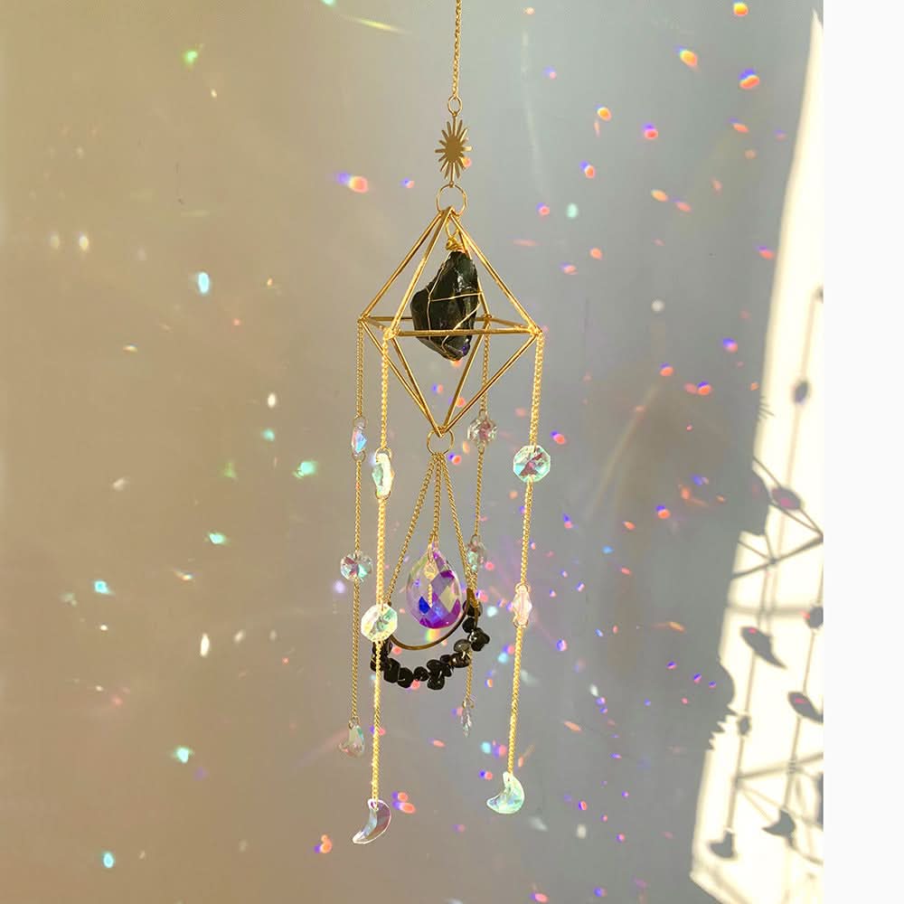 Gold crystal diamond sun catcher with prisms and dark stone, reflecting colorful light.