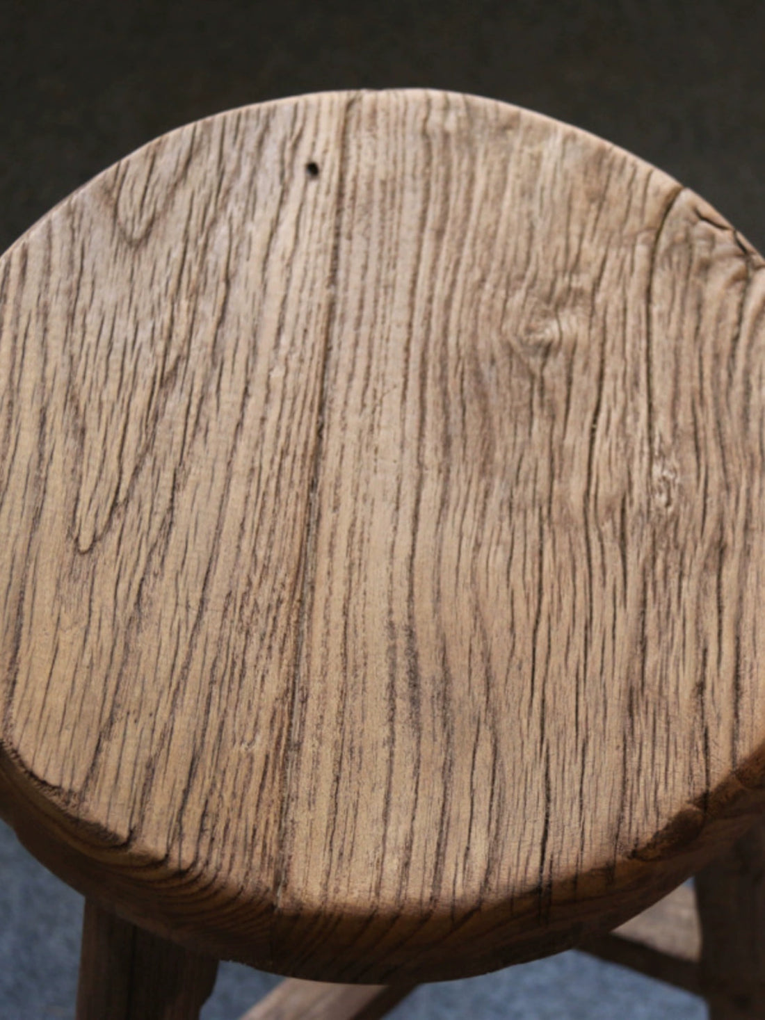 Rustic wooden stool, round top, natural wood grain.