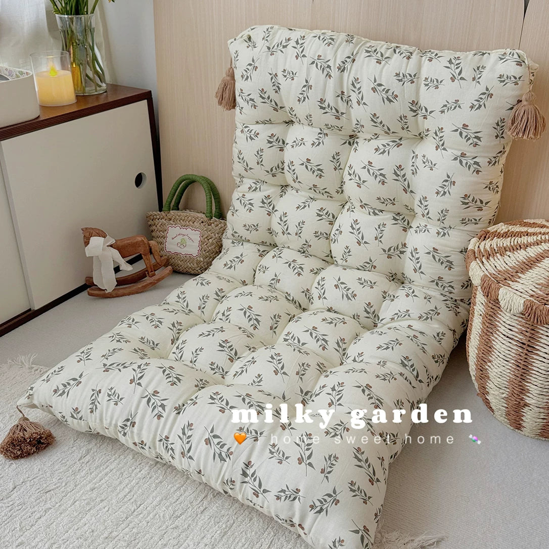 Floor cushion with gray-green leaf pattern reclined as a lounge chair, natural bedroom setting.