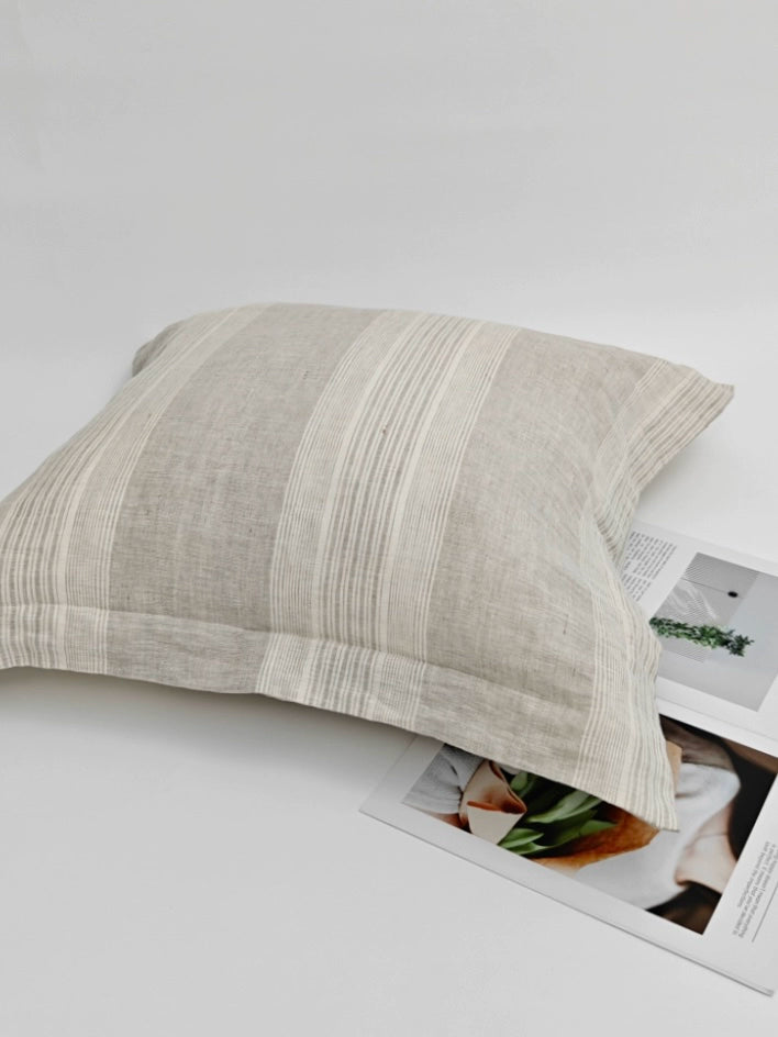 Gray striped linen pillow cover, decorative throw pillow on white surface with magazines.