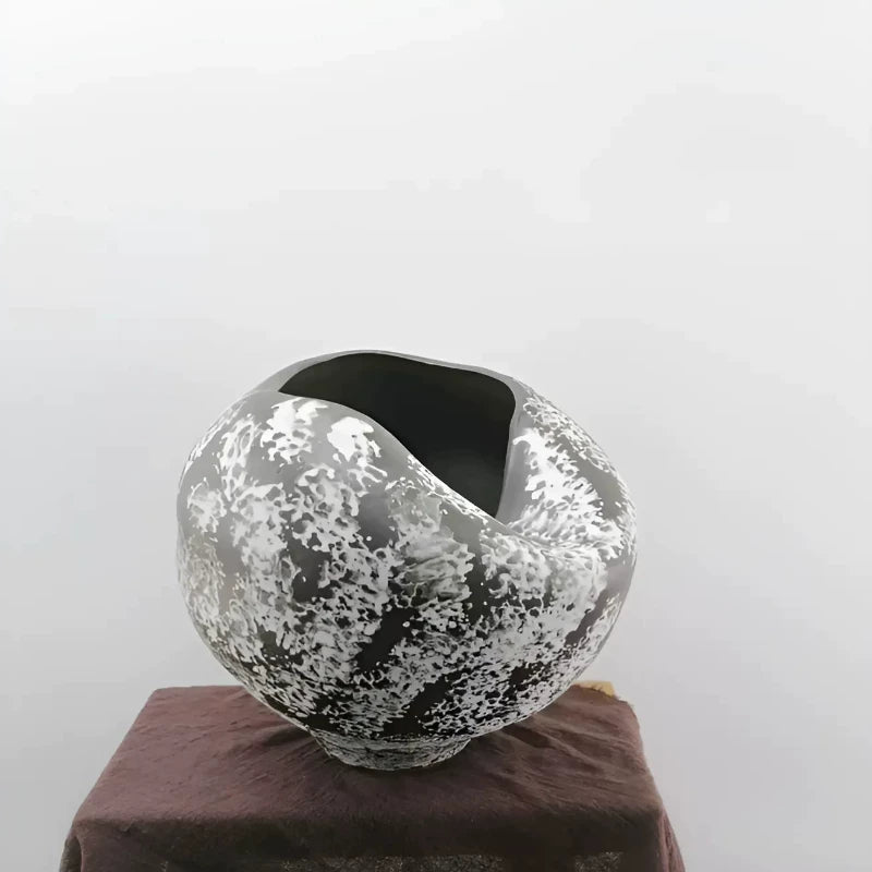 A handmade ceramic vase with a unique sculptural, folded design in a neutral beige finish.