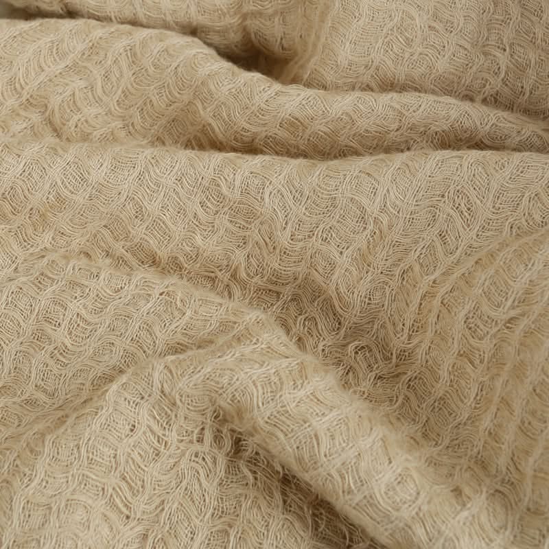 Beige linen cotton throw blanket with tassels, textured fabric detail.