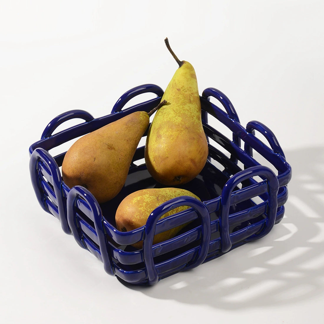 Blue ceramic fruit basket with woven design.  Pears inside.  Stylish serving dish.