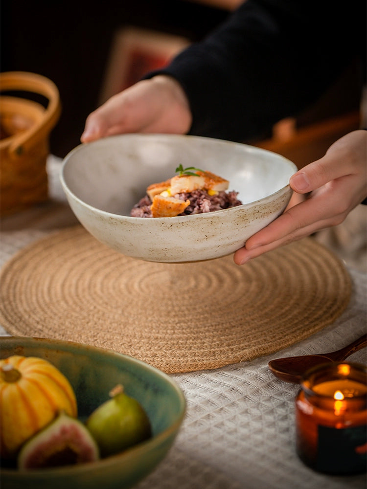 Two hand-painted ceramic bowls, light beige with speckled texture, holding food.  Rustic style, oval shape.