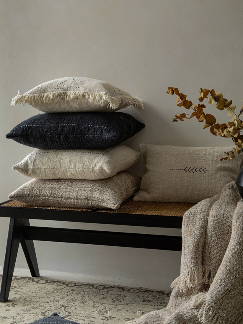 Boho throw pillows and blanket set in beige, black, natural. Woven cushions on bench.