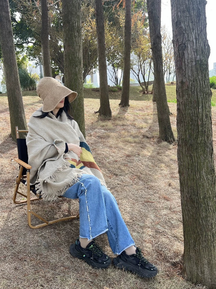 Cozy Striped Linen Throw Blanket, multicolor, draped over a person in a chair outdoors.