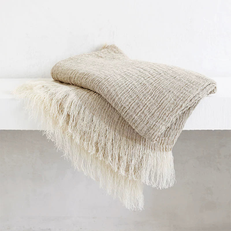 Natural linen throw blanket with fringes, beige and cream, cozy rustic decor.