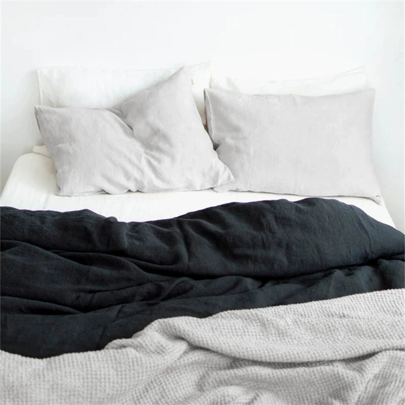 Natural linen bedding set in charcoal and light grey on a white bed. Soft, comfortable.