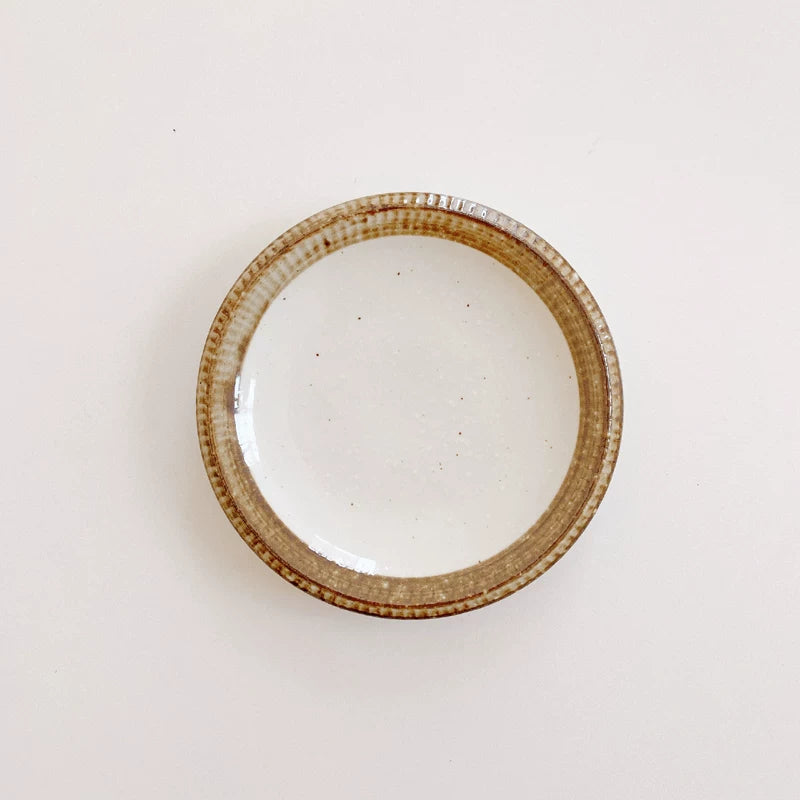 Medium-sized ceramic bowl shown from above, white speckled interior and textured brown rim.