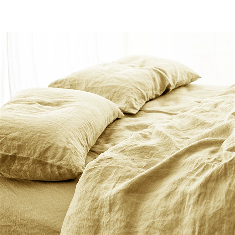 Soft natural linen bedding set in a soft yellow color, featuring comfortable pillows on a rumpled sheet.