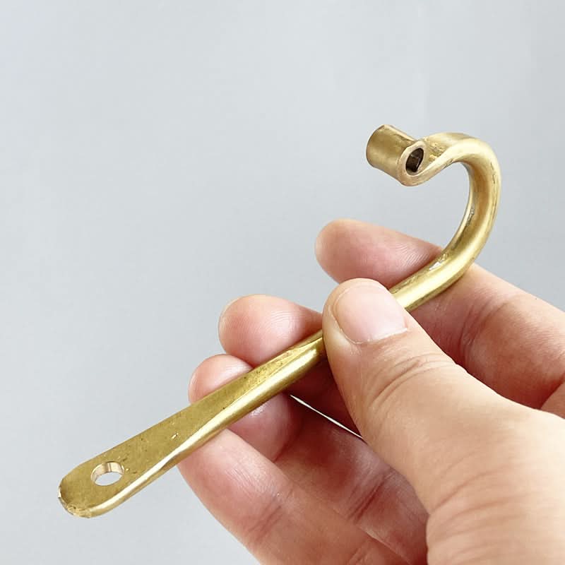 Solid brass gold J-shaped wall hook with screw hole, held in hand.