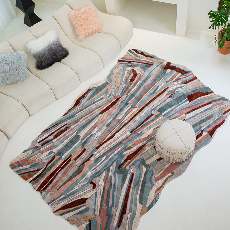 Unique Abstract Rug in blue, pink, and brown tones, laid on a white floor next to a cream sofa.