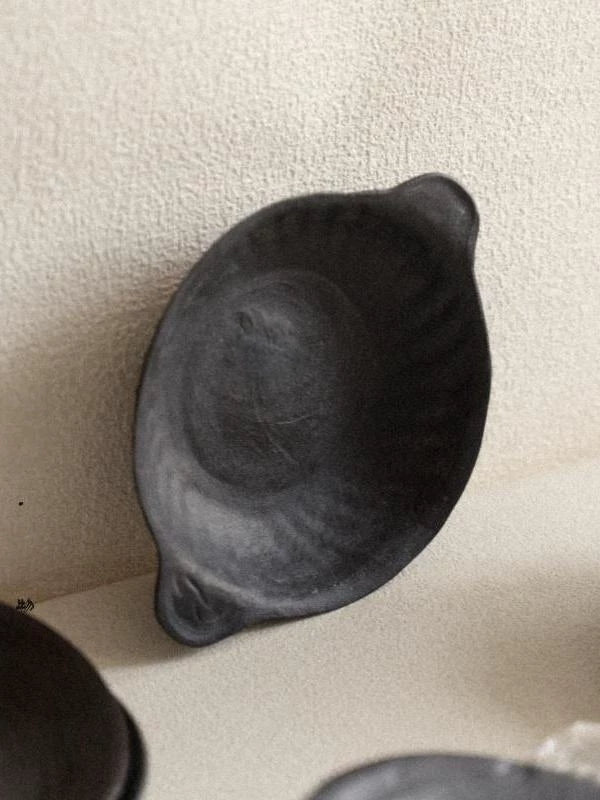 Oval matte black ceramic dish with side handles and rustic textured finish