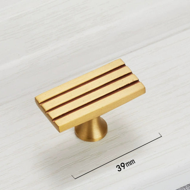 Gold toned rectangular cabinet pulls with three horizontal lines.  Single hole design.