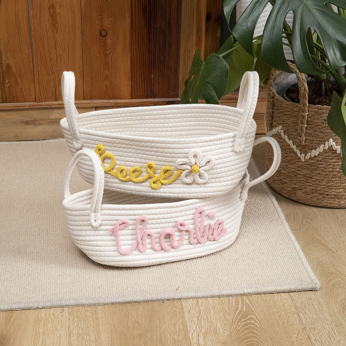 Personalized Name Woven Storage Baskets in white rope, one with yellow "Reese" & flower, one with pink "Charlie".