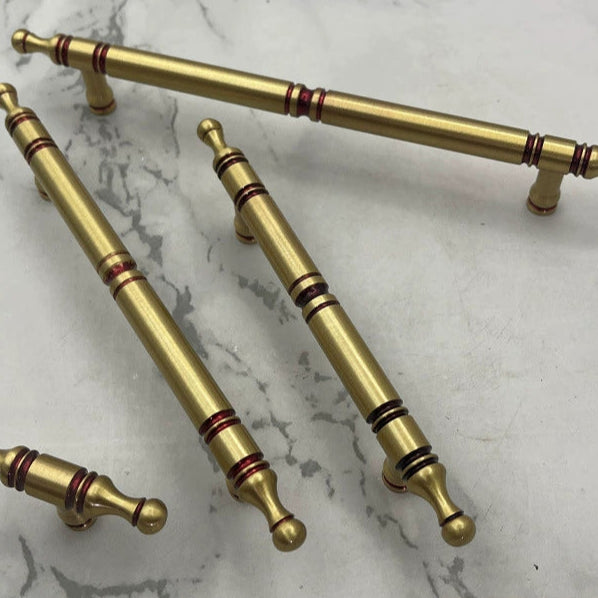 Gold cabinet handles with red accents.