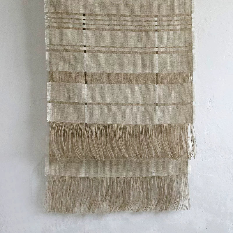 Natural beige linen table runner with fringes and stripe pattern, home decor.