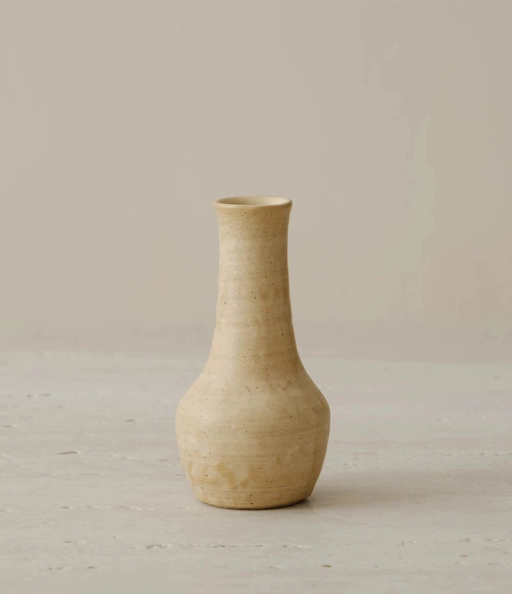 A small hand-thrown ceramic vase with a textured cream and brown glazed finish.