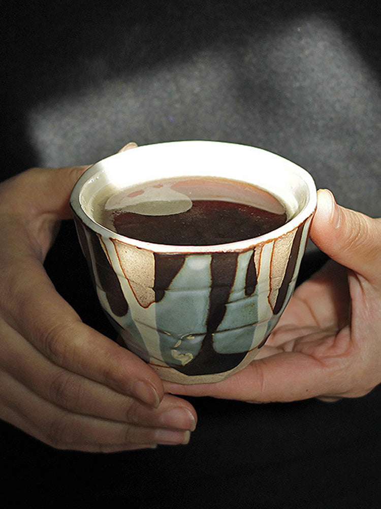 Hand holding Japanese handmade ceramic coffee cup