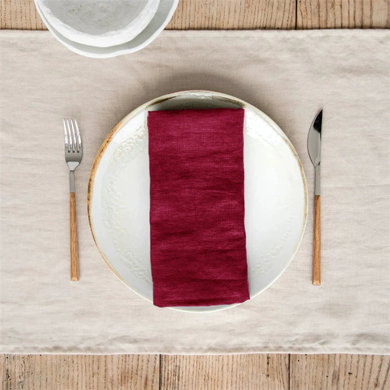 Elegant Linen Table Napkins (burgundy) on plate with fork and knife on neutral runner.