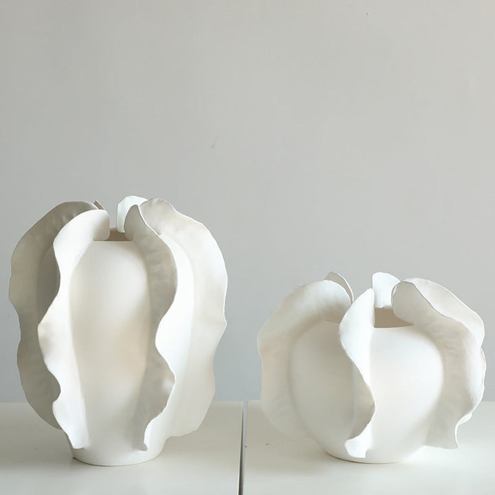 Set of modern white ruffled ceramic vases on a minimalist background.