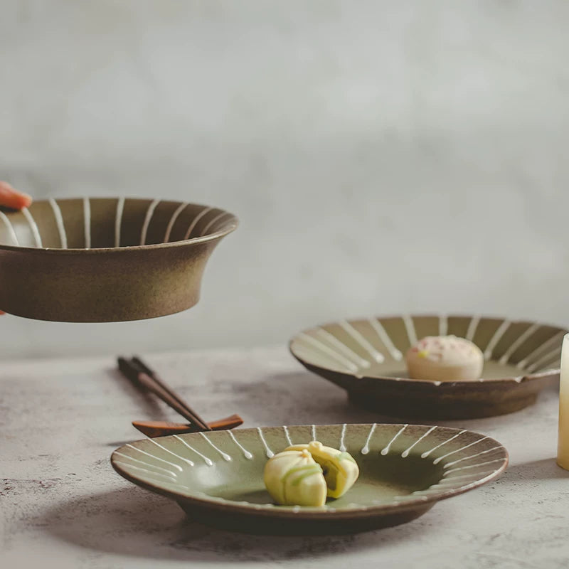 Table setting with two ceramic plates featuring green centers and white striped rims, holding pastries.