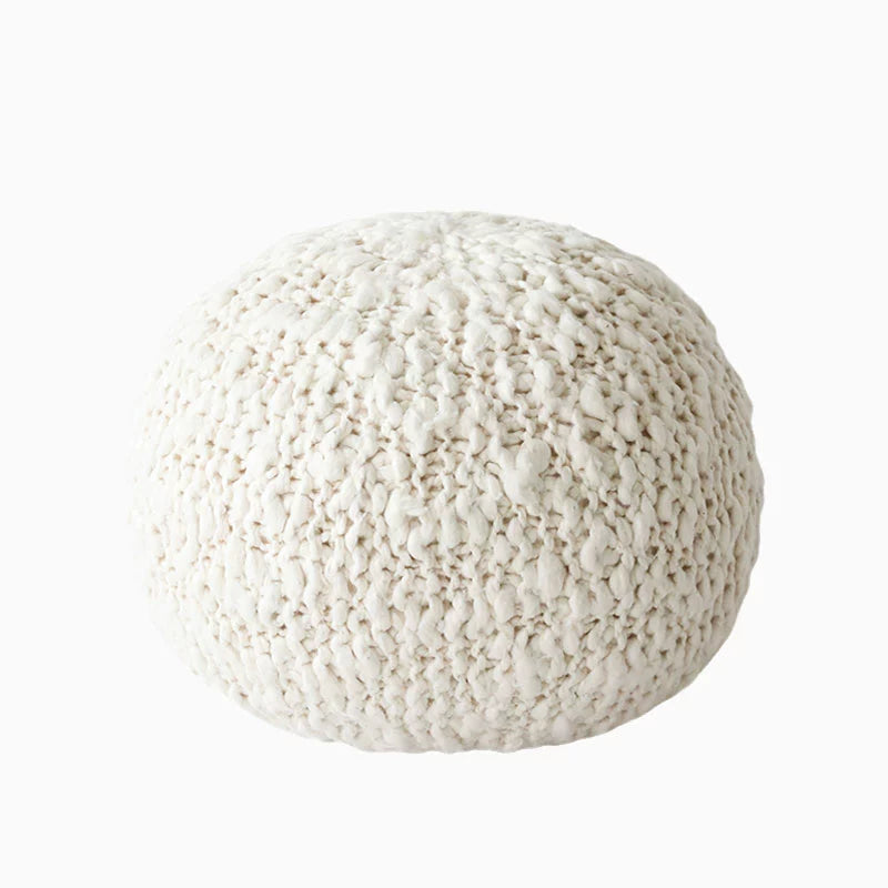 Round cream knitted throw pillow, close-up view of textured cable knit.