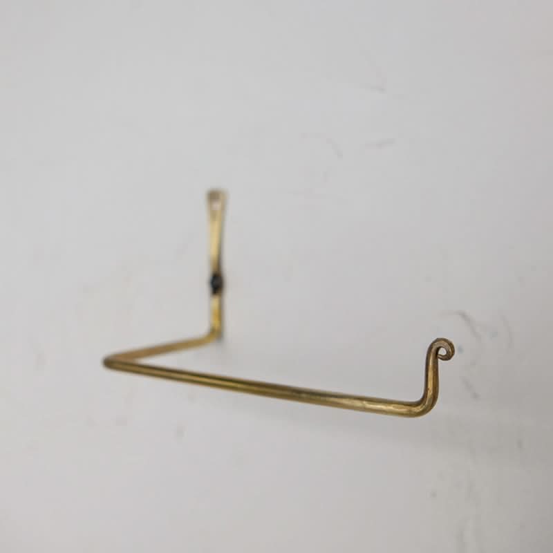 Gold toilet paper holder mounted on a white wall, sleek home decor.