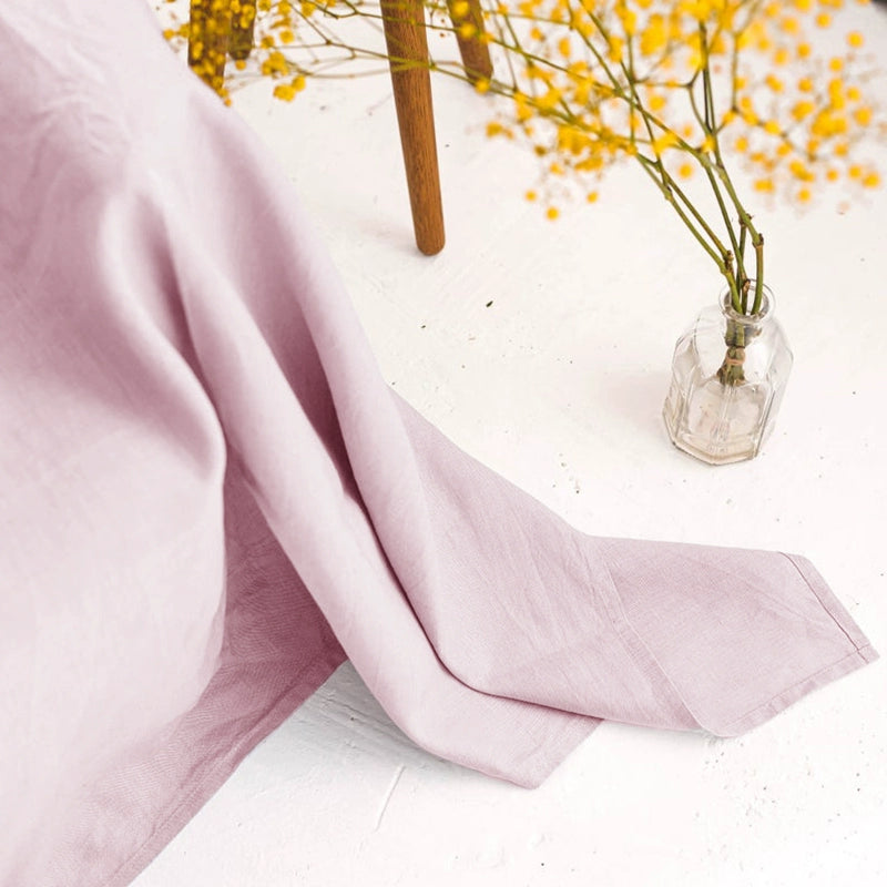 Dusty rose linen throw blanket draped over a chair with yellow flowers.