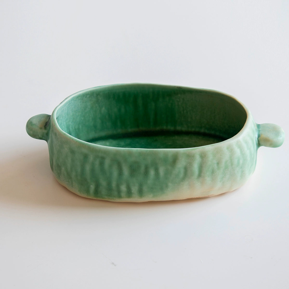 Green hand-painted ceramic serving dish with handles, part of a set.