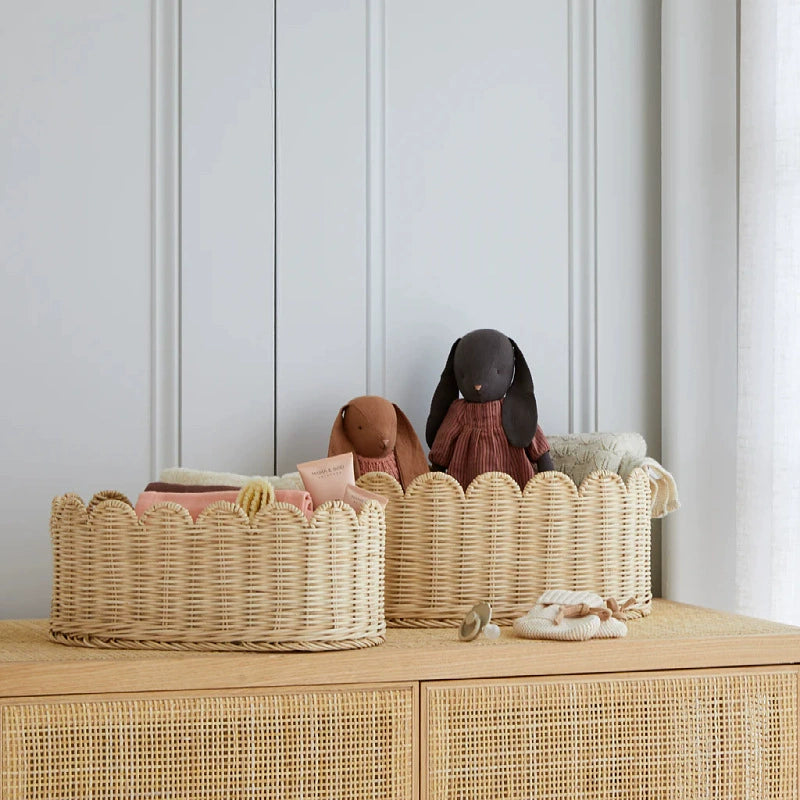 Two natural rattan baskets with scalloped edges.  Light beige wicker,  sitting on a light wood surface.