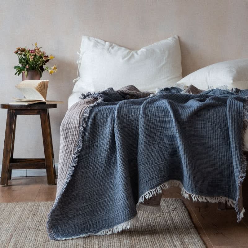 Blue Breathable Cotton Throw Blanket draped on a bed, featuring frayed edges and a cozy texture.