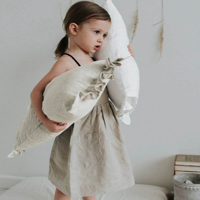 Natural linen pillow cases with frills, held by a child.