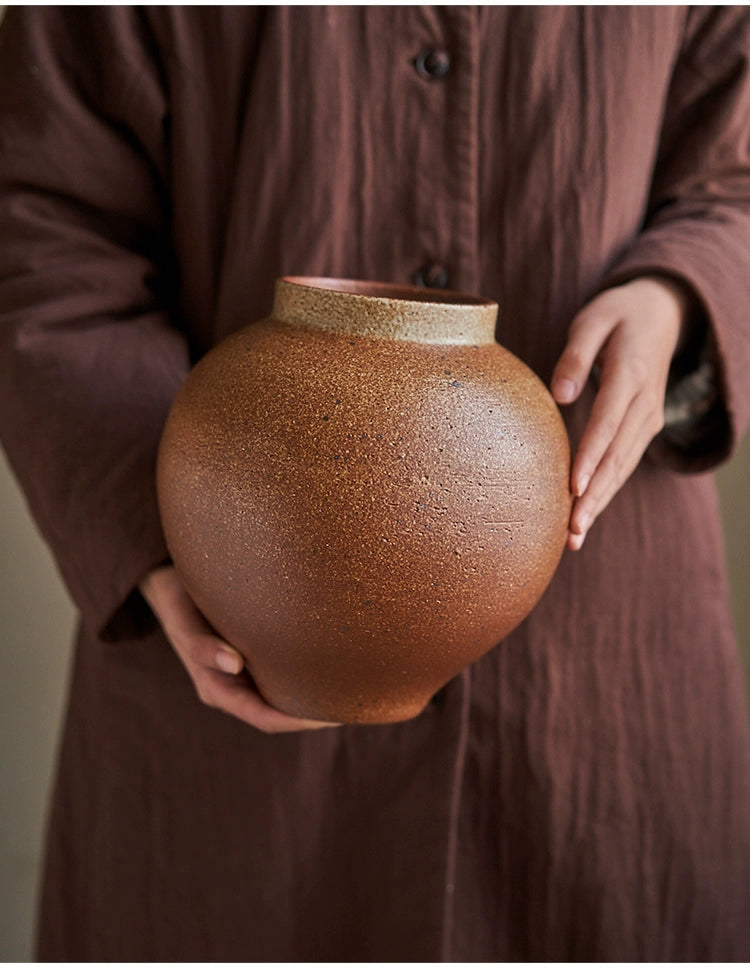 Rustic brown handmade pottery vase, textured surface, held by hands.  Unique glaze, Jingdezhen, China.