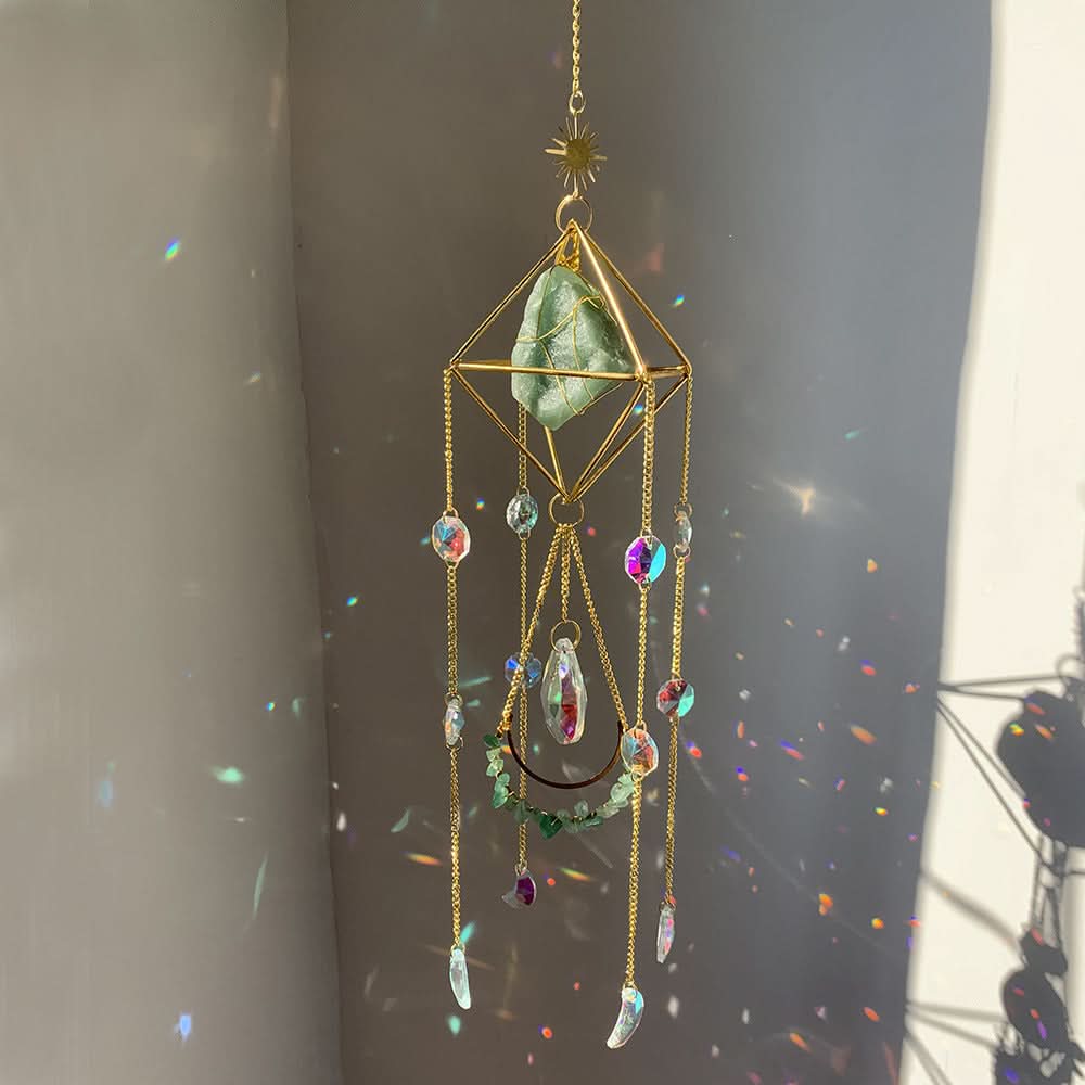 Gold crystal diamond sun catcher with green stone and rainbow prism drops, casting colorful light.