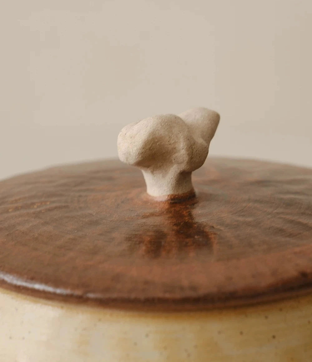 Off-white ceramic storage jar with a textured curd glaze and a natural wooden lid.