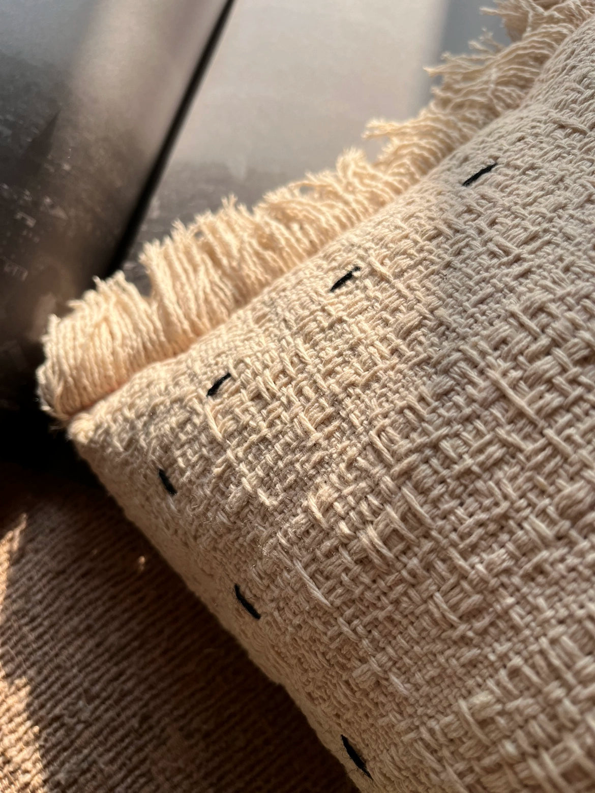 Beige woven throw pillows with fringes, textured fabric & black stitch detail