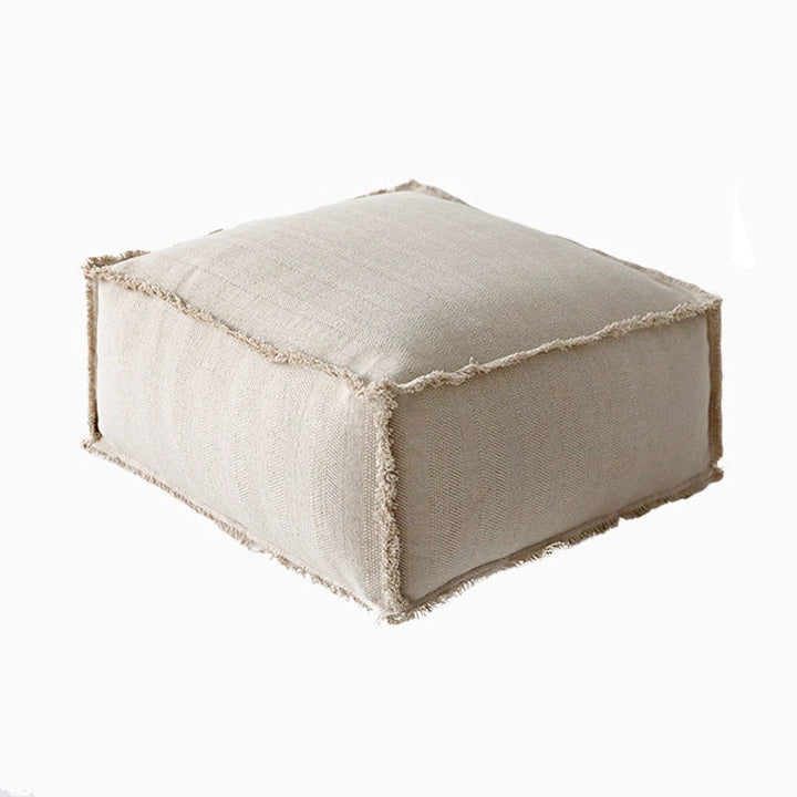Rustic taupe square fabric ottoman with frayed edges.  Cozy, decorative accent piece.