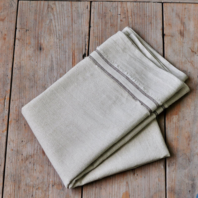 Natural beige linen tablecloth with stripes, farmhouse style, on wood table.