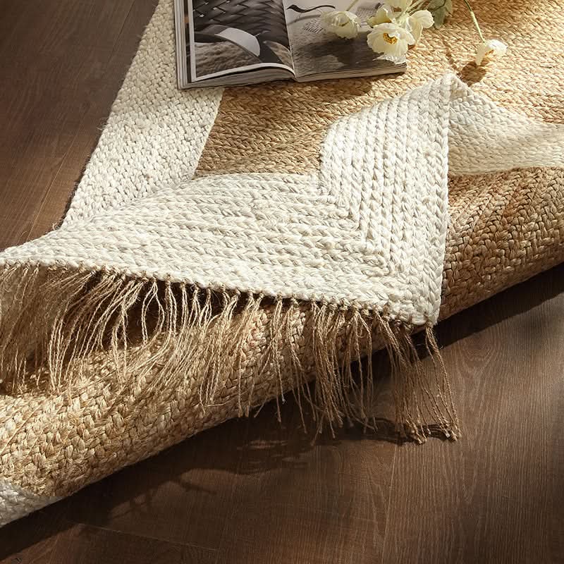 Natural jute rug with white border, fringe, and navy stripes visible on wooden floor.