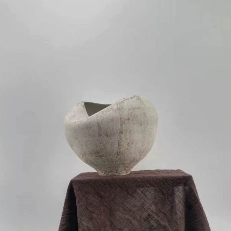 A textured white ceramic vase with a unique sculptural, folded design and a flared rim.