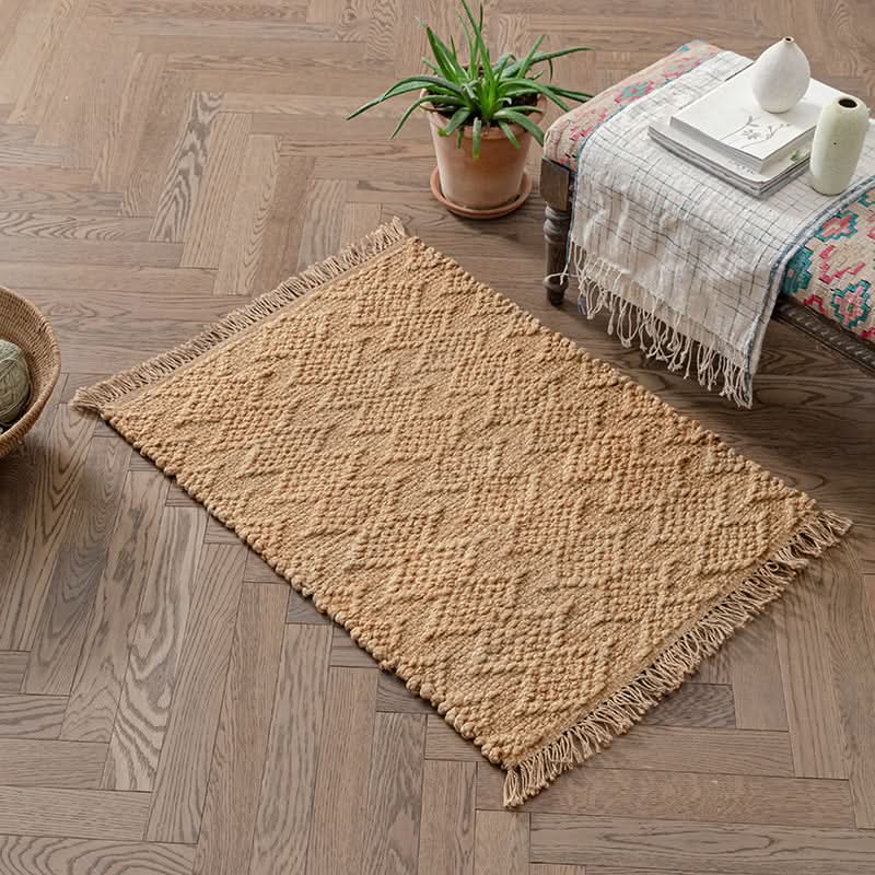 Woven Natural Area Rug with fringed edges on a herringbone wood floor.
