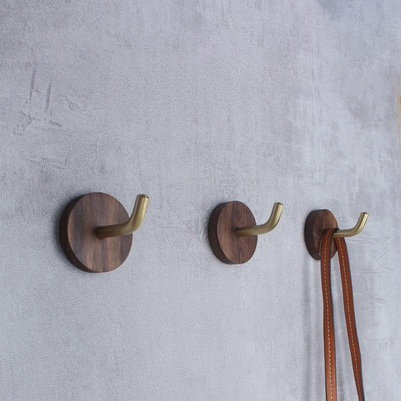 Walnut & Brass Wall Hooks on grey textured wall, holding brown leather straps.