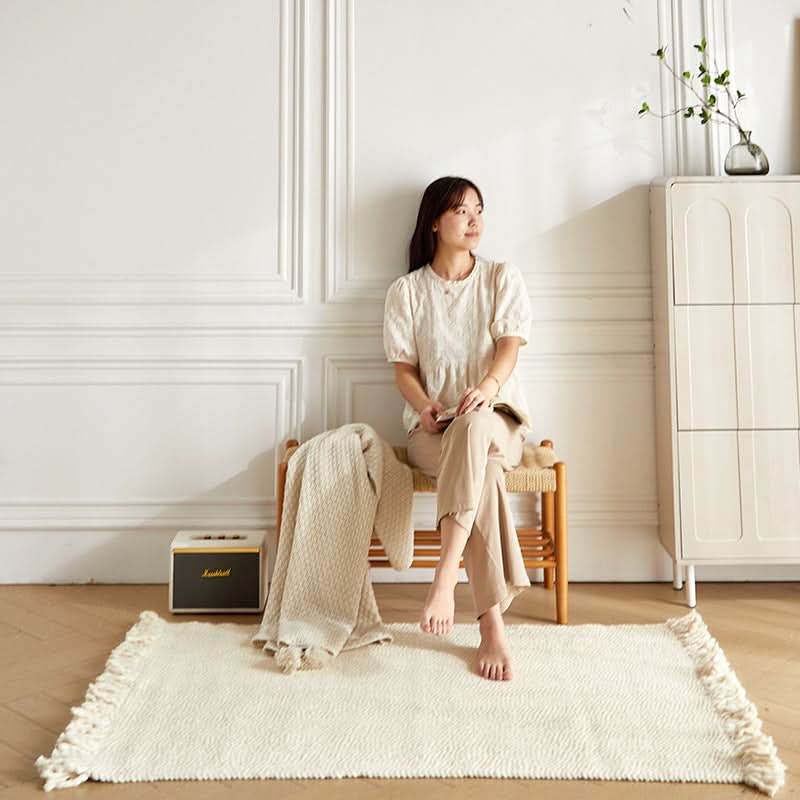 Off-white braided wool rug with fringe detail, styled in a modern living room.