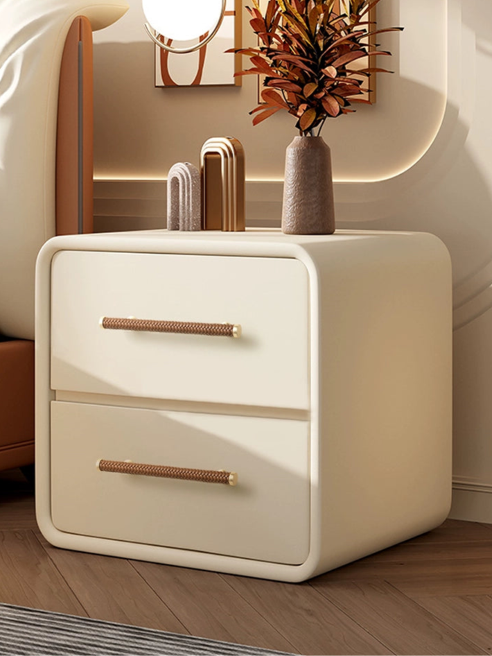 Woven leather drawer pulls, gold tone, on cream-colored drawers.  Braided brown leather handles.