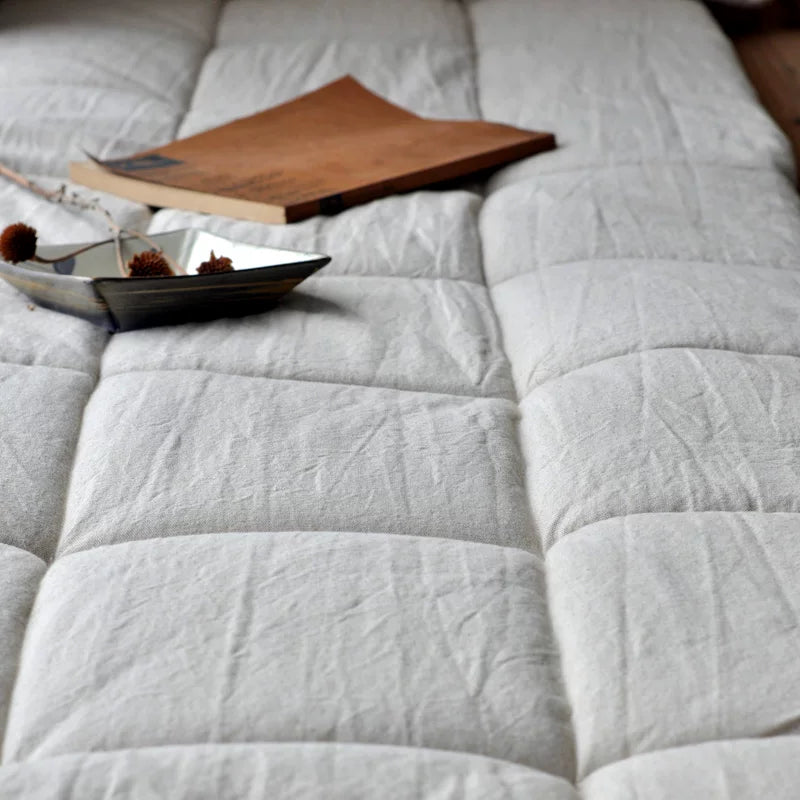 Close-up of a white quilted mattress surface, focused on the texture and items placed on it.