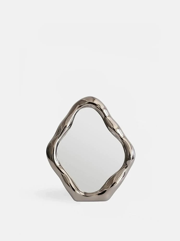 Modern abstract silver metal vanity mirror, organic shape, on a white background.
