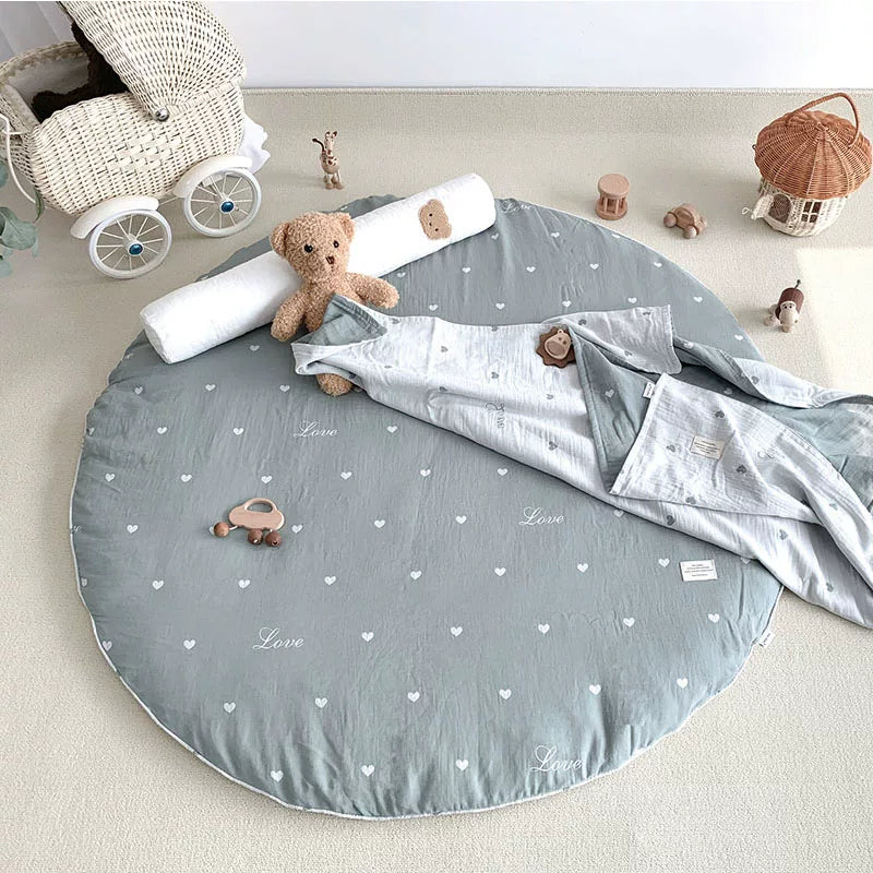 Round grey-blue heart-print baby mat with a teddy bear, blanket, and doll stroller.